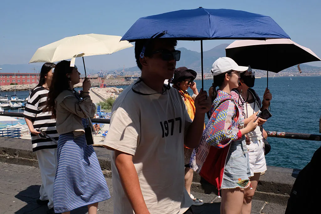People shield themselves from the sun during the African heatwave in Naples, on July 20.