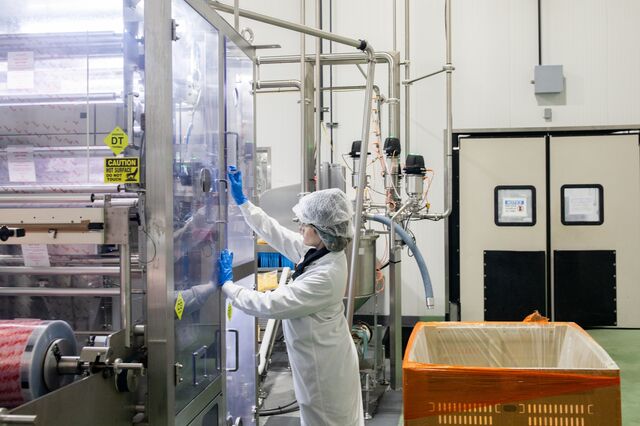 A worker observes the machine that seals packages of lemonade concentrate. 