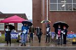 Precinct and campaign volunteers hold umbrellas while standing outside a polling station in Leesburg, Virginia.