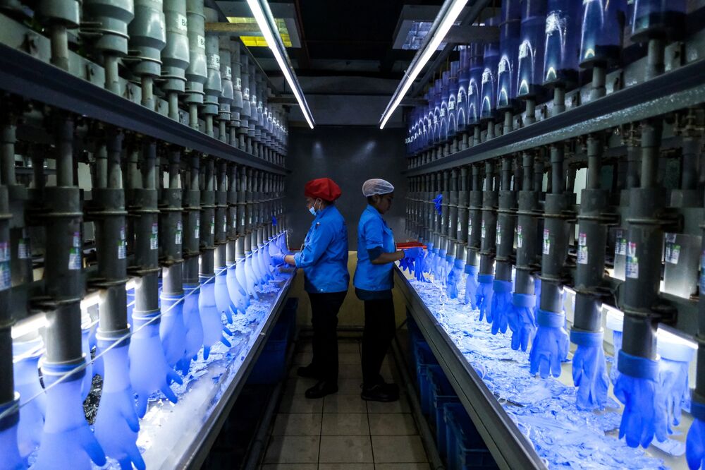Employees check latex gloves in the watertight test room at a Top Glove factory in Malaysia.