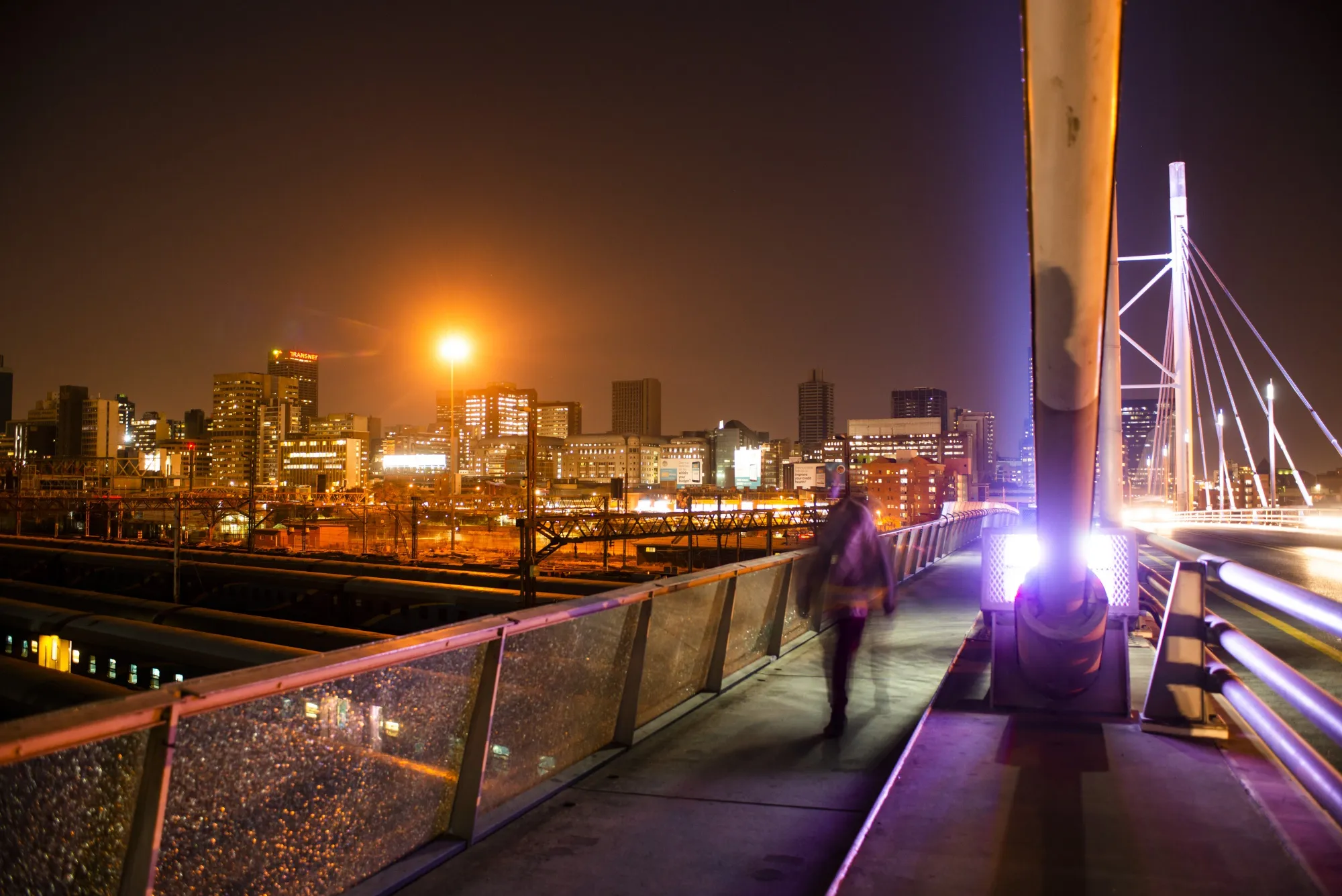 A pedestrian walks across Nelson Mandela bridge at night in the central business district of Johannesburg, South Africa.