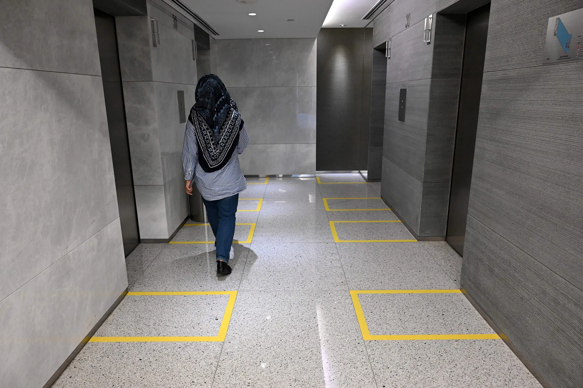 Taped off areas to distances people in the lift lobby of an office building in Singapore.