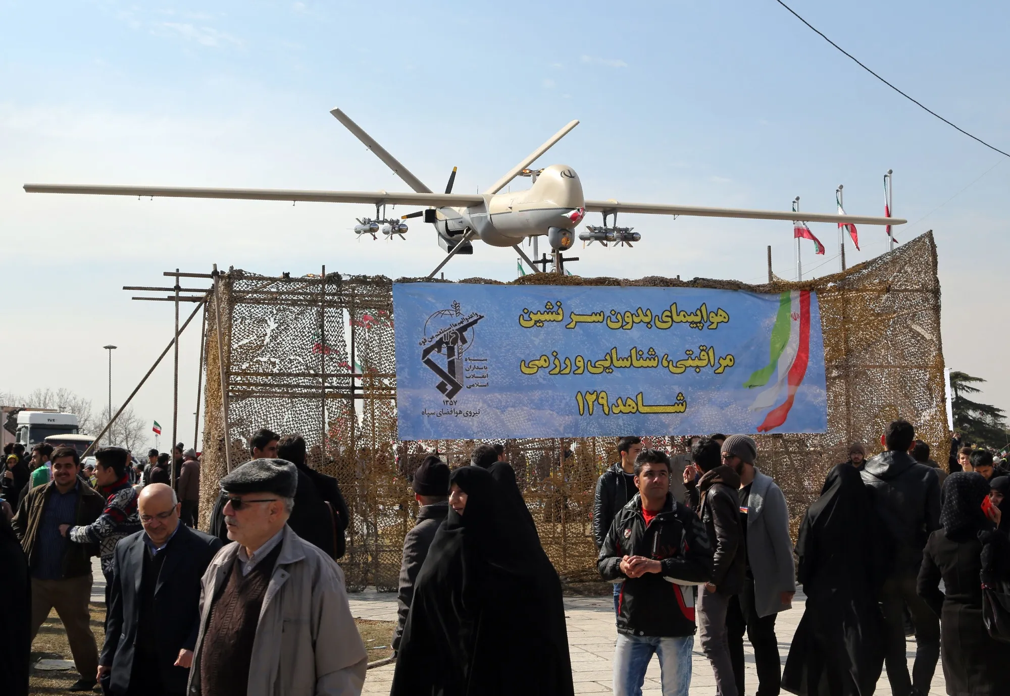 Iranians walk past Iran's Shahed 129 drone in Tehran.&nbsp;