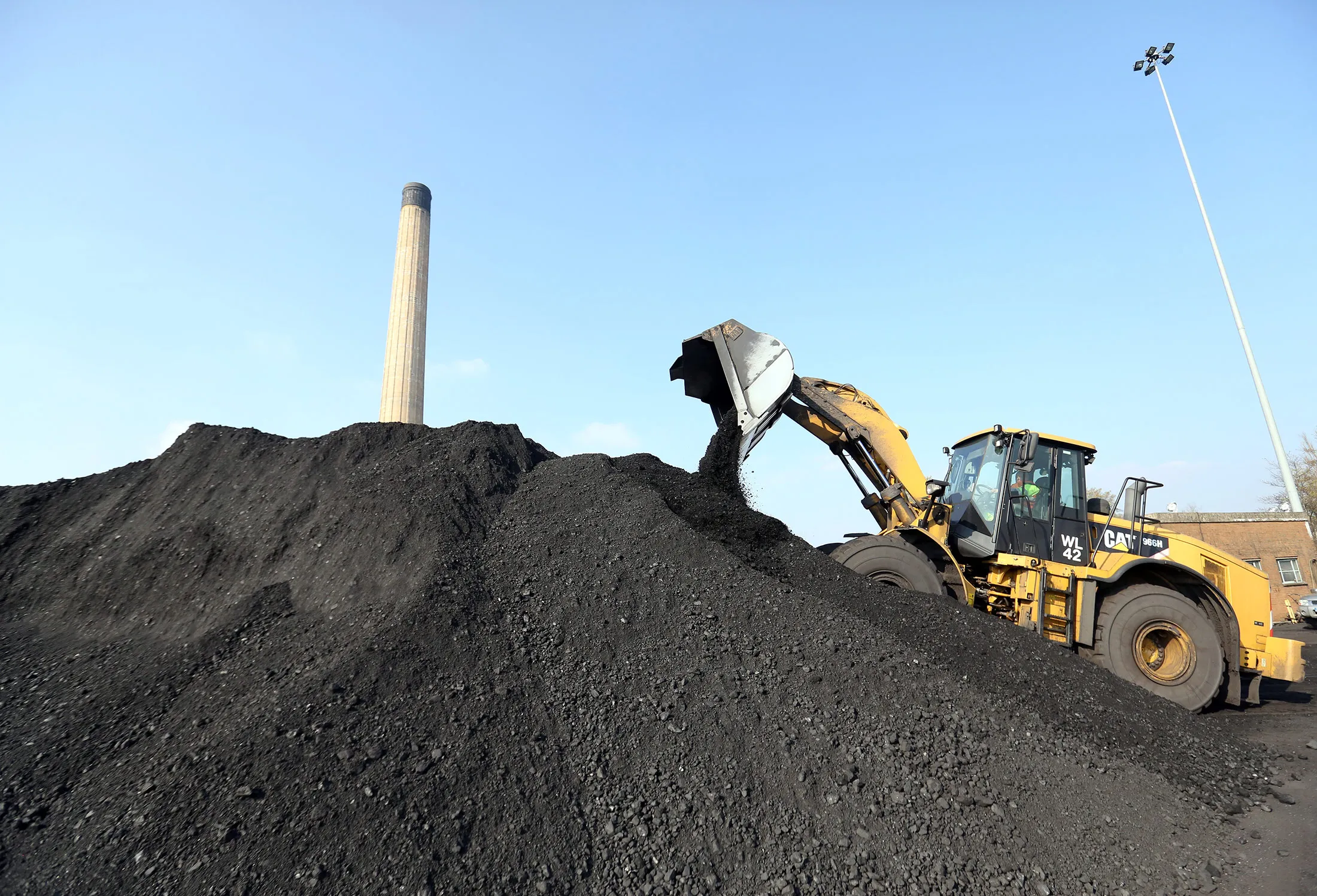 A digger moves coal into a hopper machine at Uskmouth power station, operated by Simec Uskmouth Power Ltd., in Newport, U.K., on Thursday, March 17, 2016. The former coal-fired station based on the east bank of the Usk estuary, will be converted to generate energy using biomass.
