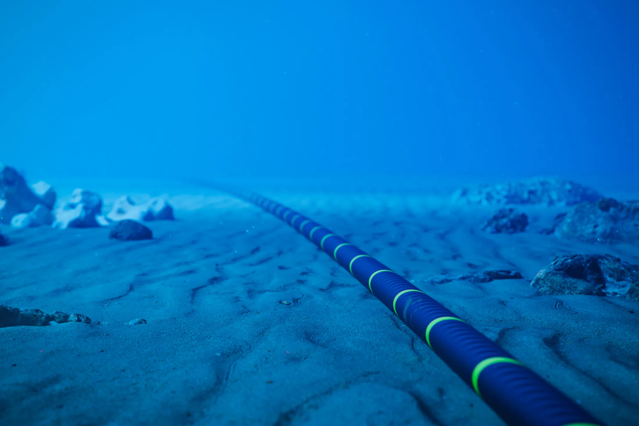 Underwater fiber-optic cable on ocean floor.