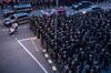 Motorists ride past riot police in Bangkok on Oct. 15.