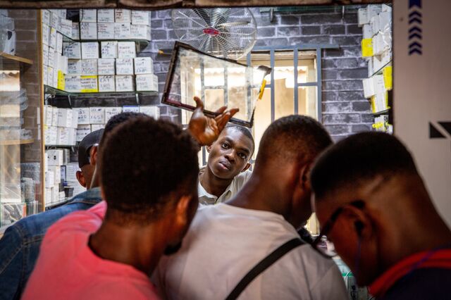A vendor displays a tablet screen guard to a customer at a phone repair and hardware kiosk at the Ikeja computer village market in Lagos, Nigeria, on Monday, March 29, 2021. Nigerians are having to contend with the highest inflation rate in four years, the second-highest unemployment rate on a list of 82 countries tracked by Bloomberg, and an economy that’s only just emerged from recession.