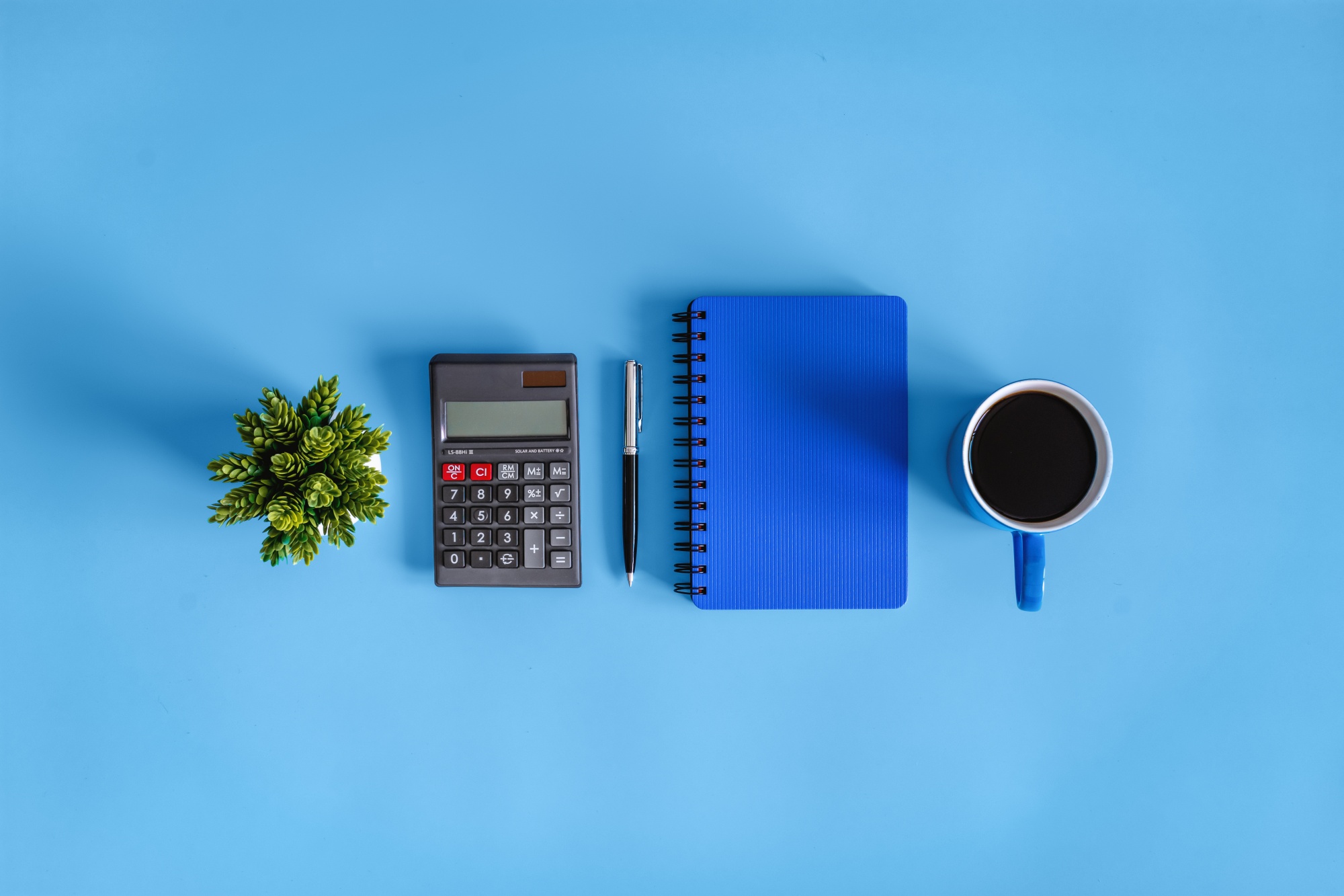 Coffee Break. Calculator and Notebook on Blue Desk.
