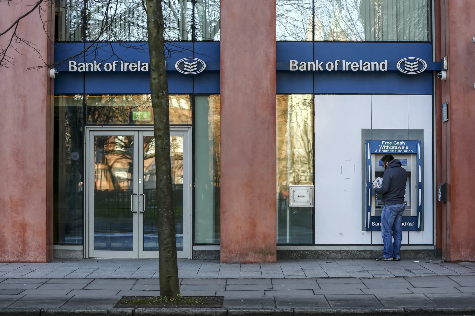 A customer uses an ATM&nbsp;at a Bank of Ireland Group Plc branch in Belfast, Northern Ireland.