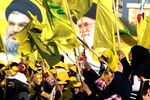 Women wave a Lebanese national flag and Lebanese Shiite movement Hezbollah flags in front of portraits of Iran's supreme leader Ayatollah Ali Khamenei (R) and Hezbollah leader Hassan Nasrallah, in the southern Lebanese town of Bint Jbeil on August 13, 2016.