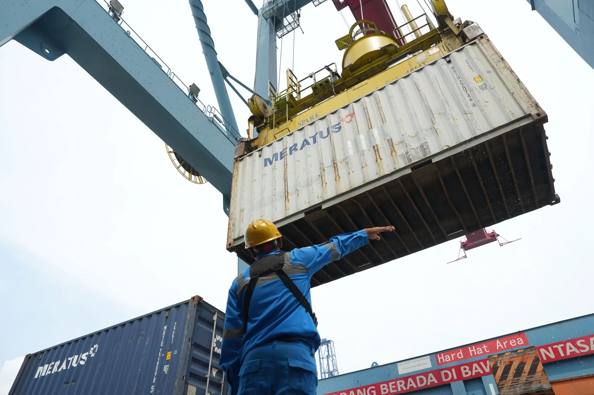 An employee directs a shipping container while its loaded onto a truck at the IPC Container Terminal at Tanjung Priok Port in Jakarta