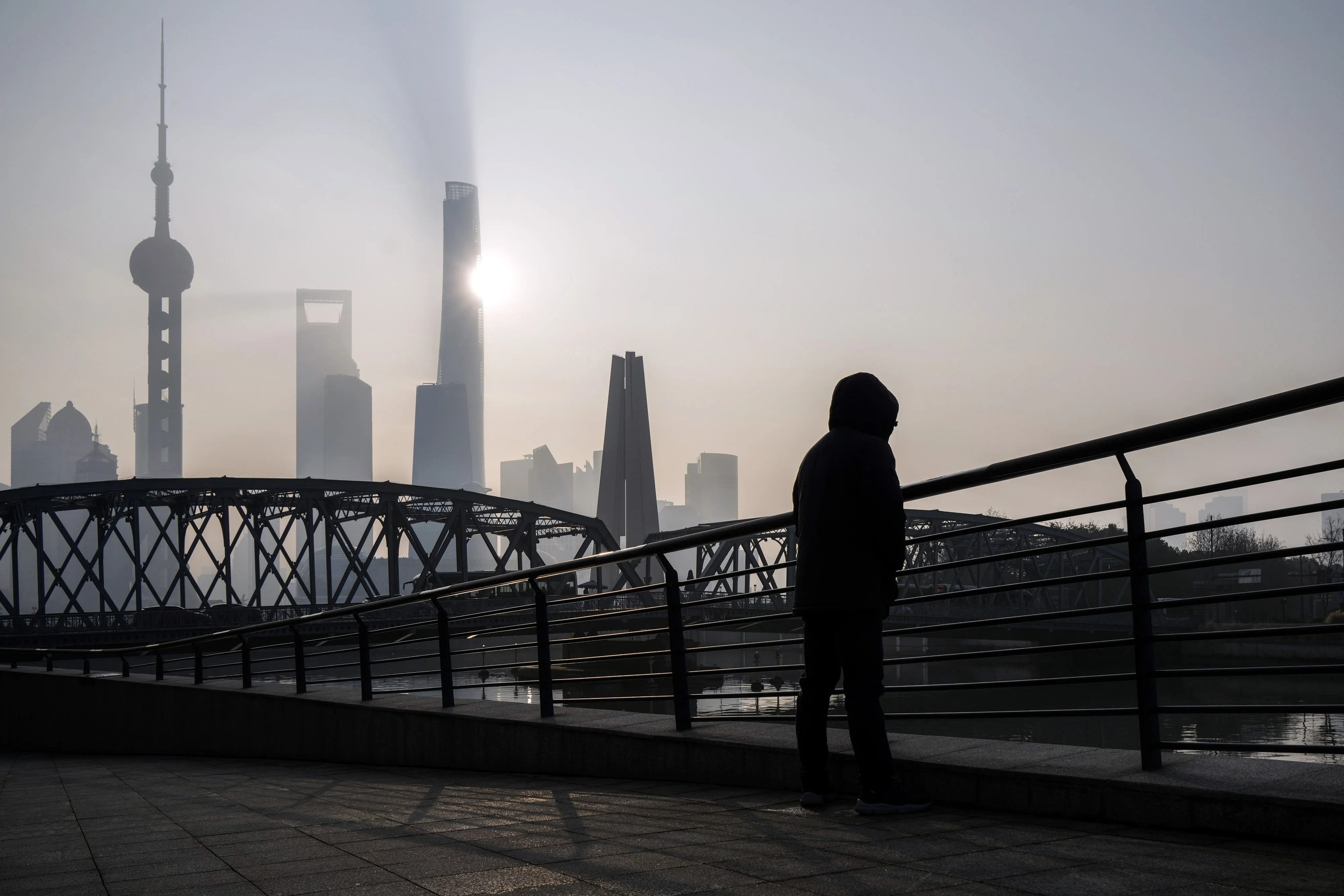 A pedestrian along a bridge passes buildings in Pudong's Lujiazui Financial District in Shanghai, China.