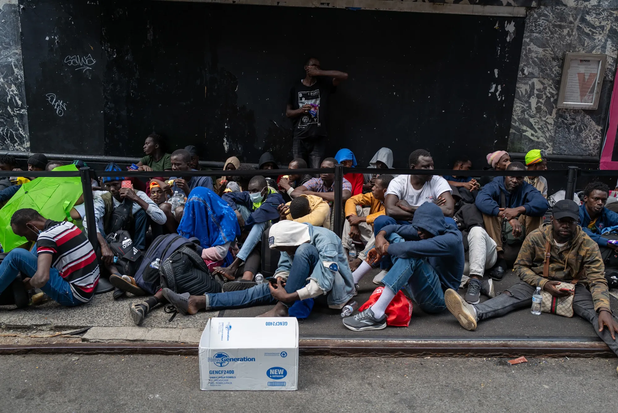 Recently arrived migrants wait outside the Roosevelt Hotel in&nbsp;New York City.&nbsp;