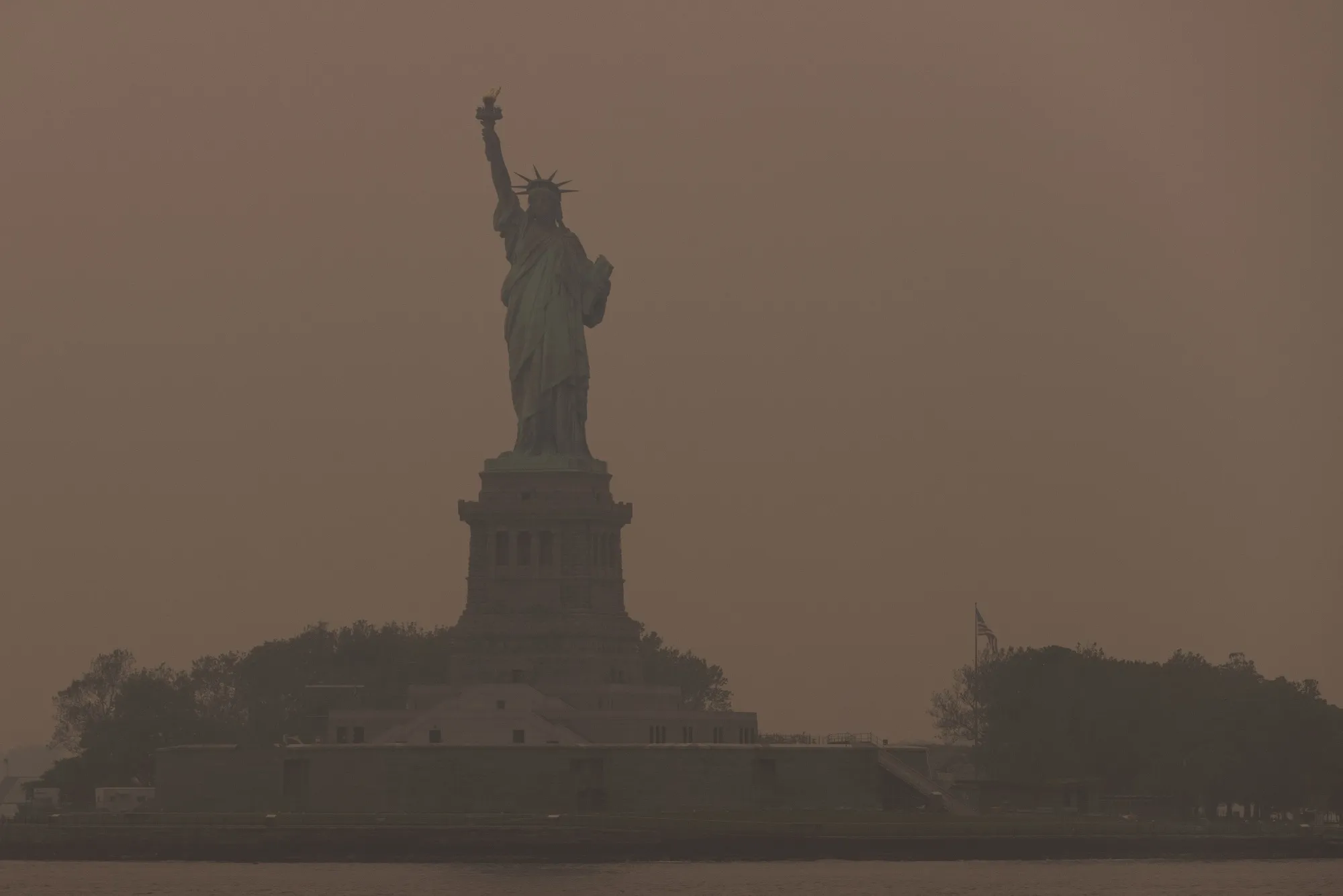 The Statue of Liberty shrouded in smoke from Canada wildfires in New York on June 7, 2023. A new petition seeks to formally classify extreme heat and wildfire smoke in the US as major disasters.