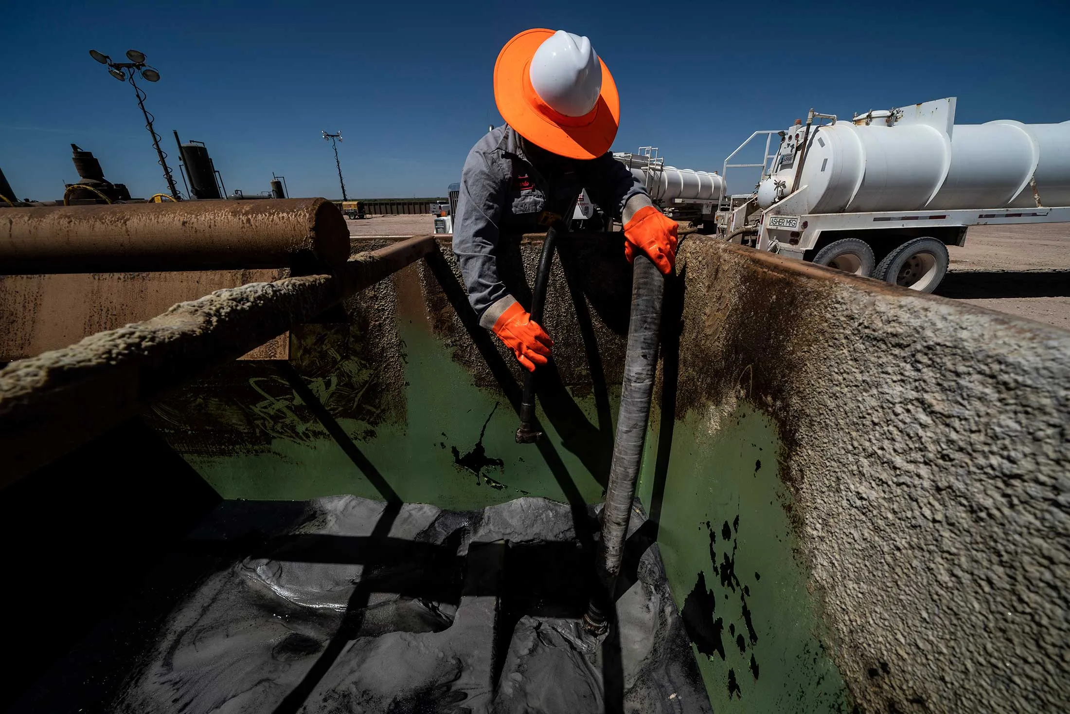Workers extracting oil from wells in the Permian Basin in Midland, Texas.&nbsp;