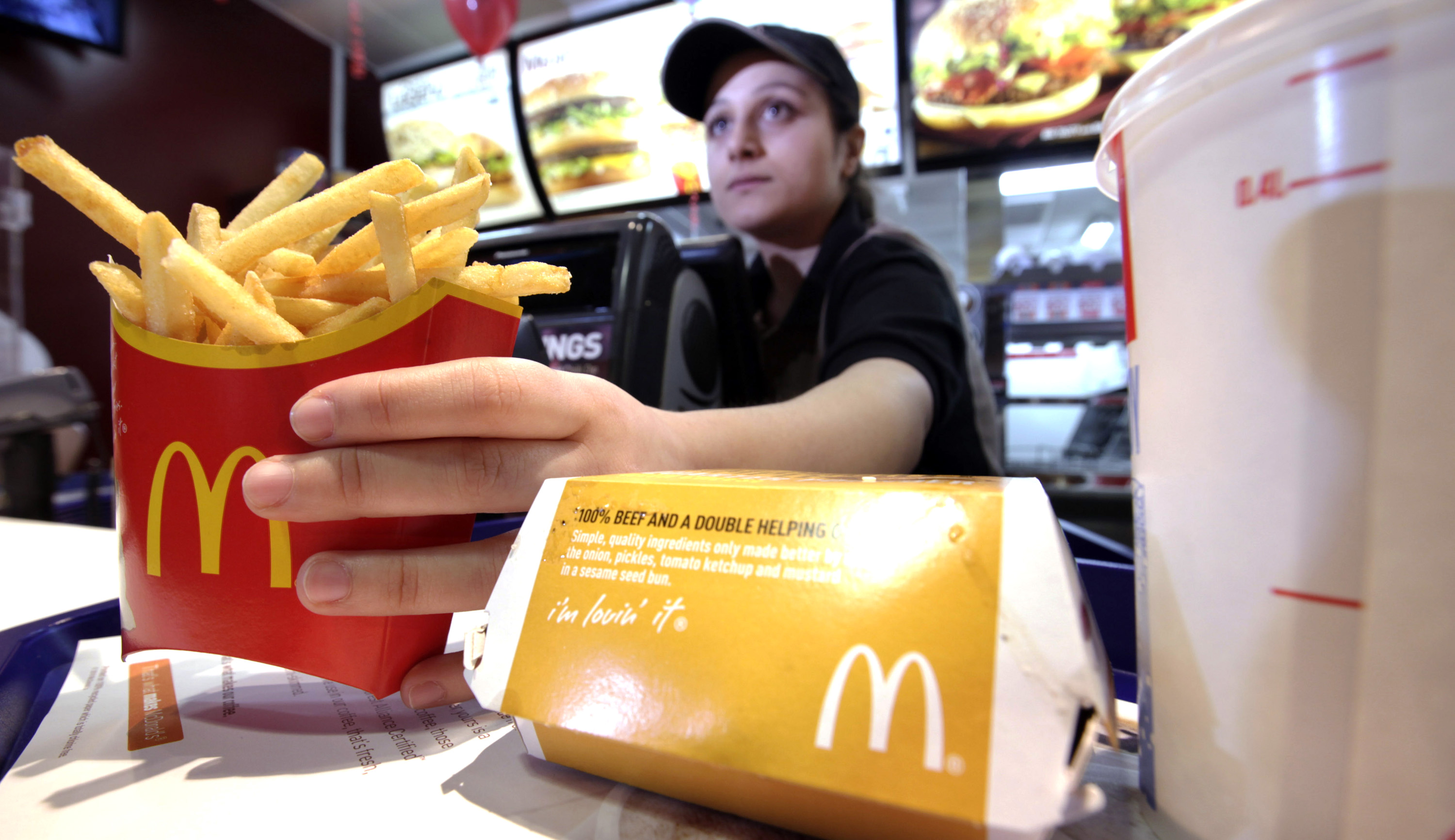 A McDonald's employee serves a burger and a carton of french fries at one of the company's restaurants.