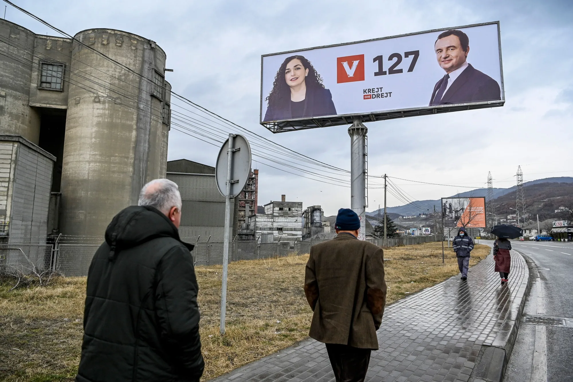 Pedestrians walk past a&nbsp;billboard depicting&nbsp;Albin Kurti and Kosovo's acting President Vjosa Osmani, in Hani i Elezit, ahead of Kosovo elections.