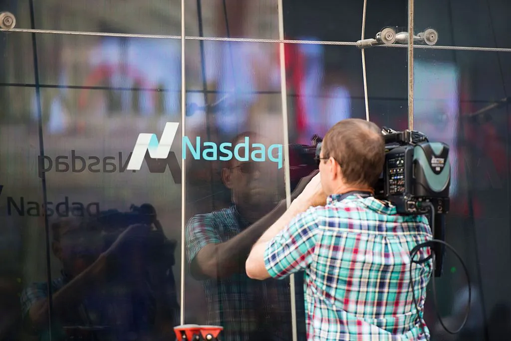 A TV cameraman shoots video through the windows of the Nasdaq offices in Times Square on June 24, 2016 in New York.
