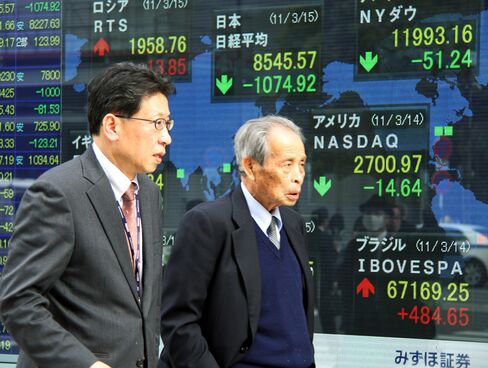 Pedestrians walk past an electronic stock board outside a securities firm in Tokyo. Commodities fell.