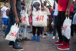 Customers hold Hennes &amp; Mauritz AB (H&amp;M) shopping bags outside a store in New York, U.S., on Saturday, Sept. 23, 2017.&nbsp;