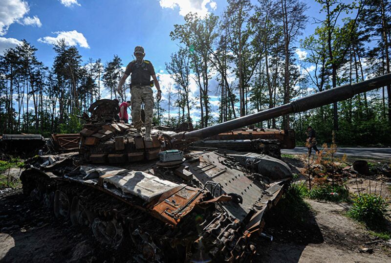 A man looks at a destroyed Russian tank at Dmytrivka village