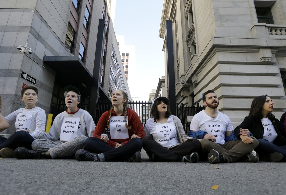 Protesters lock arms as they block a driveway at the U.S. Citizen and Immigration Services building in San Francisco on May 1, 2017.