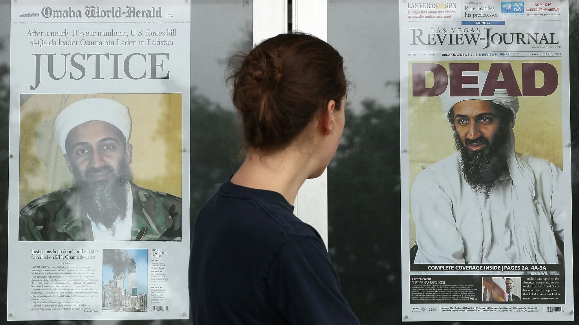 A passer by looks at newspaper headlines reporting the death of Osama Bin Laden, in front of the Newseum, on May 2, 2011 in Washington, DC.
