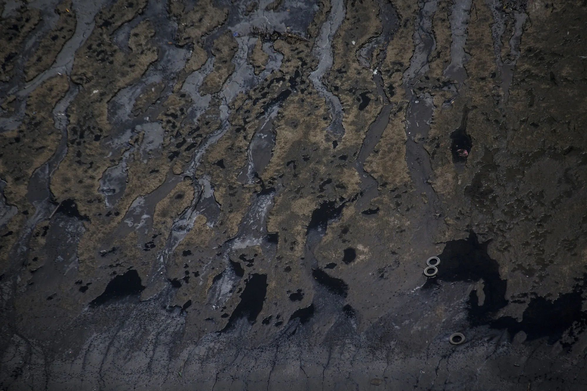 Dark sand stands as tidal water recede from a beach in which sewage spills into the waters of Guanabara bay in Rio de Janeiro, Feb. 13, 2016.
