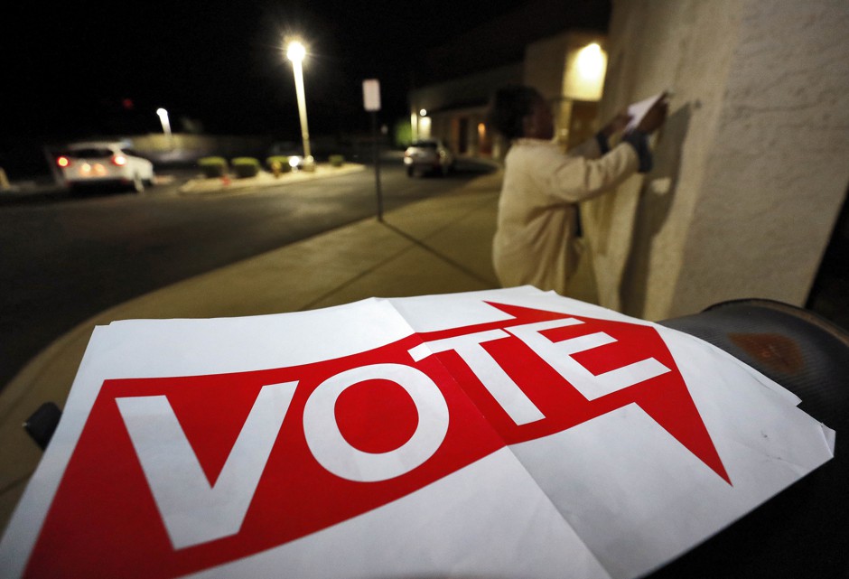 An election official hangs &quot;Vote&quot; signs outside a polling station in Phoenix, Arizona.