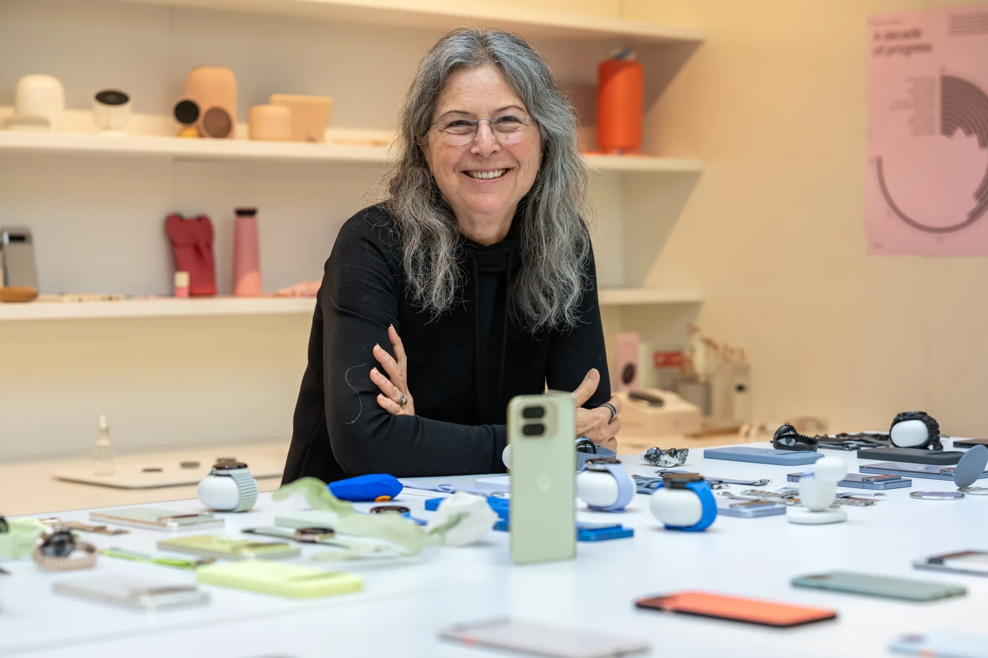 Портрет Айві Росс, яка спирається на стіл, застелений різними продуктами Google Pixel