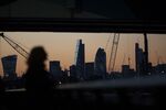 A woman looks out onto the City of London skyline from the Canary Wharf business, financial and shopping district of London, U.K.
