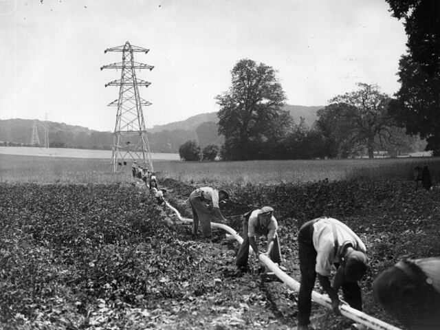Workmen connect pylons by laying 33,000 volt cables in rural Berkshire, UK, in August 1933.