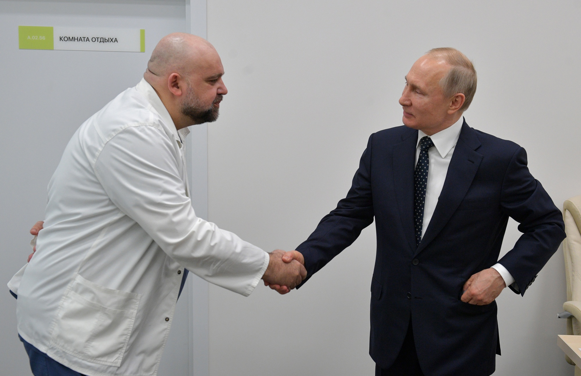 Vladimir Putin shakes hands with Denis Protsenko on his visit to the Novomoskovsky medical center, in Moscow, on March 24.
