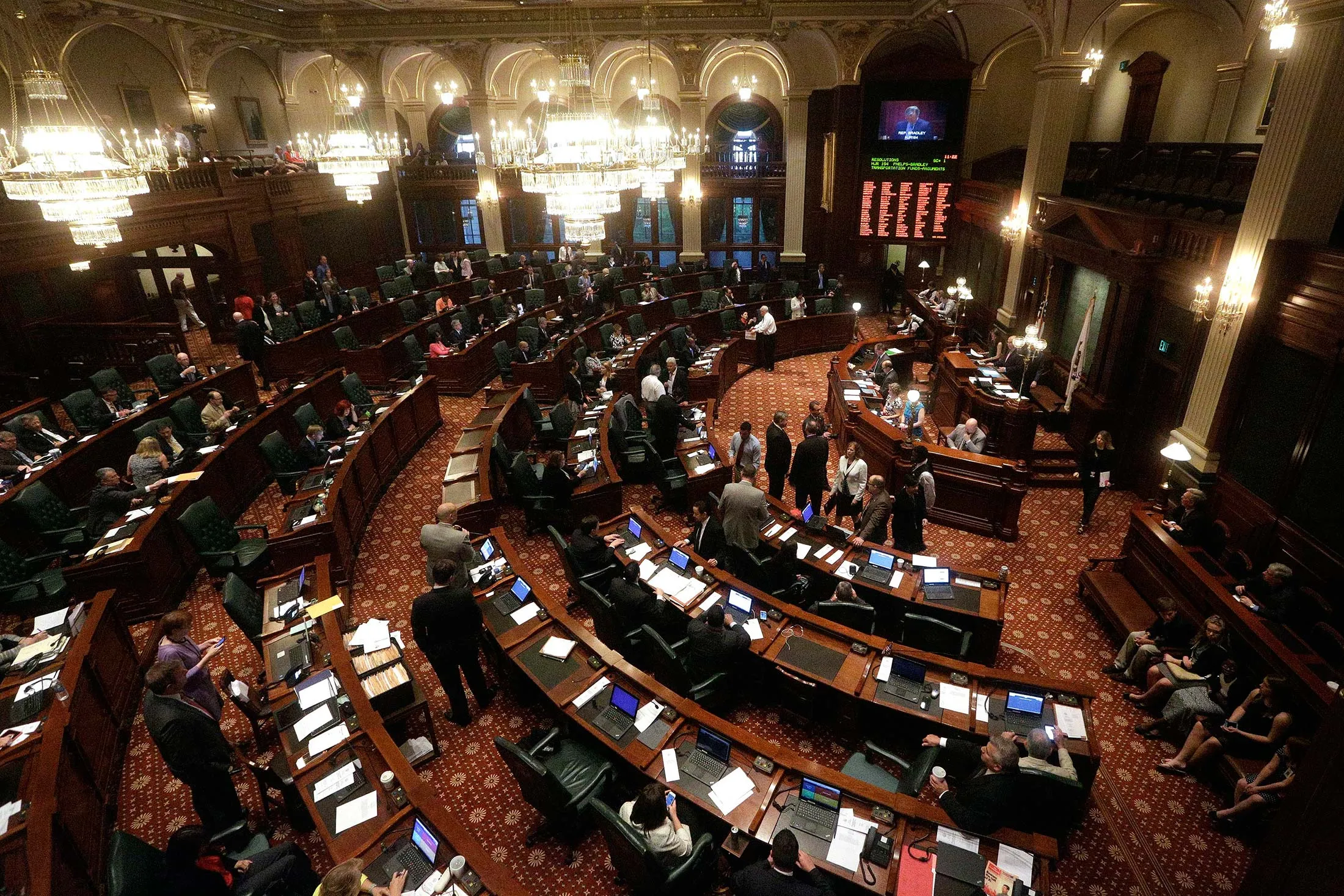 Illinois representatives gather on the House floor during session at the Illinois State Capitol Tuesday, May 31, 2016, in Springfield, Ill., as lawmakers press ahead on the last day of the spring legislative session. Illinois Gov. Bruce Rauner proposed a short-term budget fix on Tuesday in a last-ditch effort to give the state some temporary stability during a nearly yearlong spat between the Republican and Democratic lawmakers over a spending plan.
