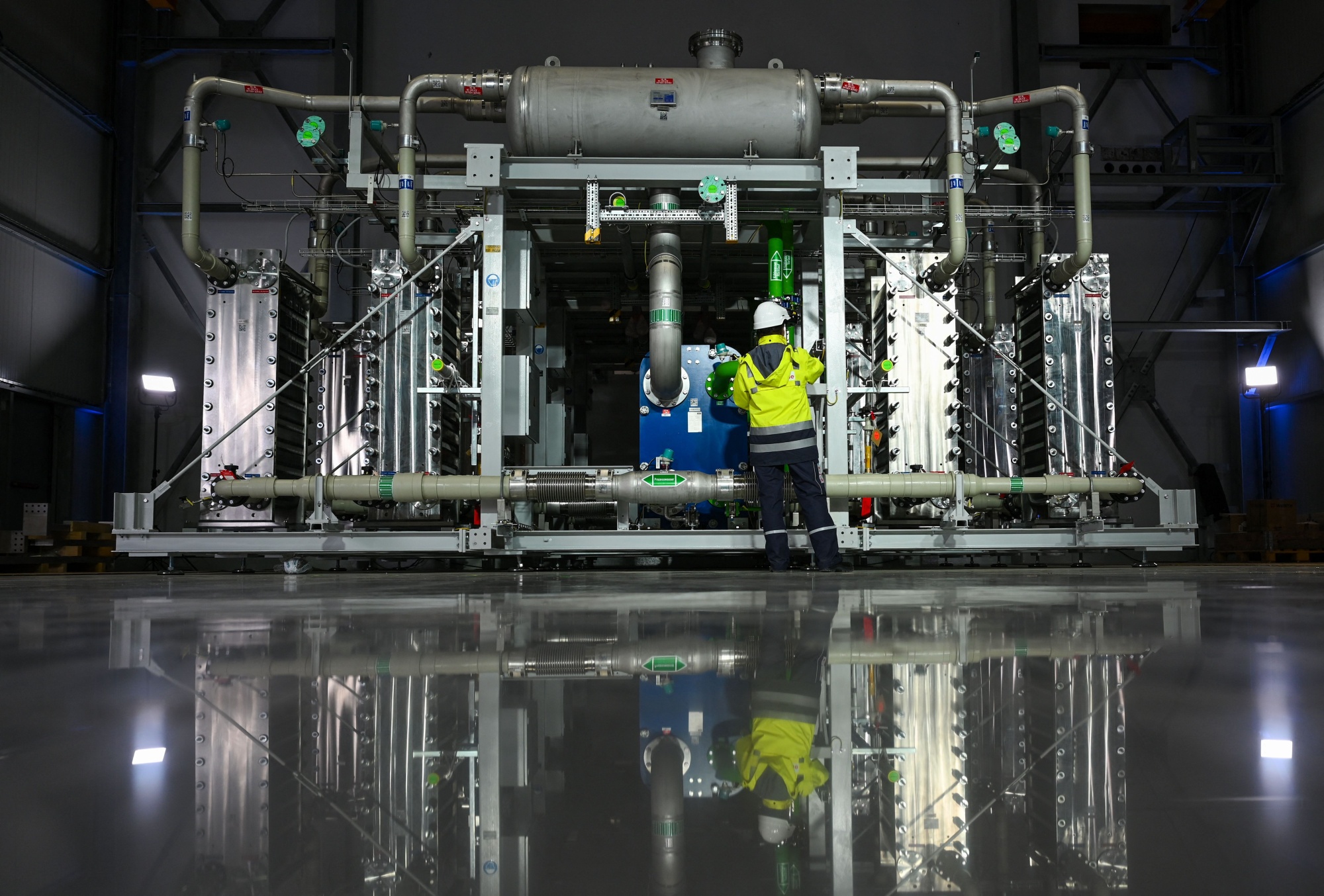 An employee stands in front of an electrolyzer at a hydrogen production facility of renewable hydrogen in Oberhausen, Germany.