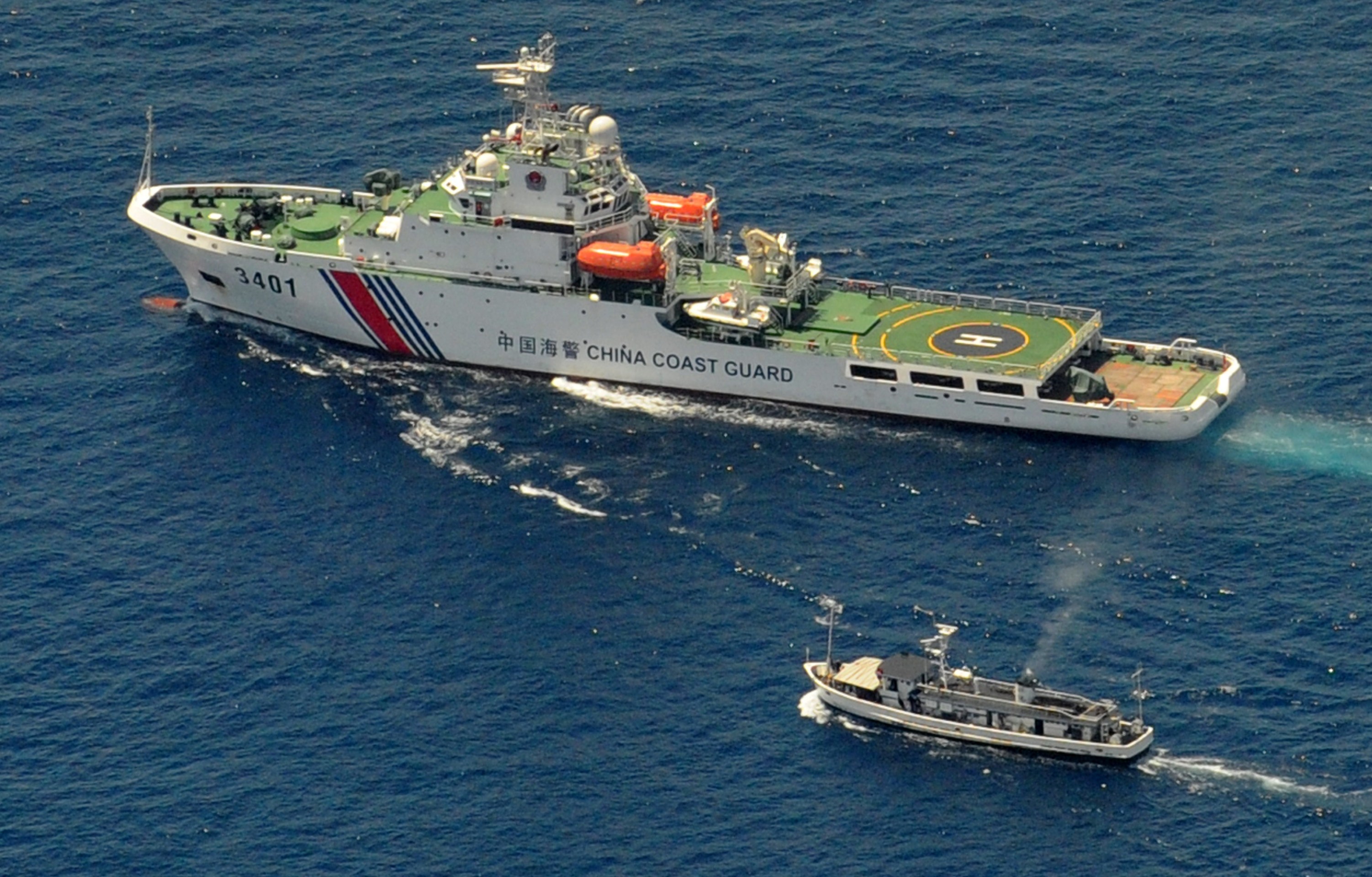 A China Coast Guard ship (top) blocks a Philippine boat from reaching a reef in South China Sea claimed by both countries in 2014.
