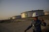 An employee walks past crude oil storage tanks at the Juaymah Tank Farm in Saudi Aramco's Ras Tanura oil refinery and oil terminal in Ras Tanura, Saudi Arabia, on Monday, Oct. 1, 2018. Saudi Arabia is seeking to transform its crude-dependent economy by developing new industries, and is pushing into petrochemicals as a way to earn more from its energy deposits.