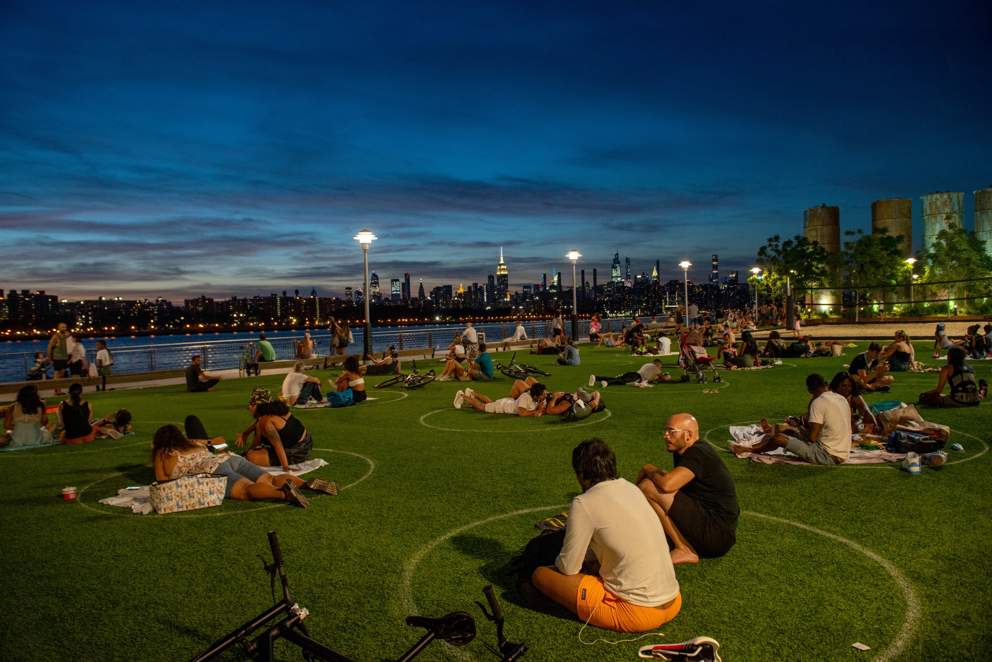 People sit in circles to observe social distancing in Domino Park in Brooklyn,&nbsp;with a view of the Manhattan skyline,&nbsp;on July 26, 2020.