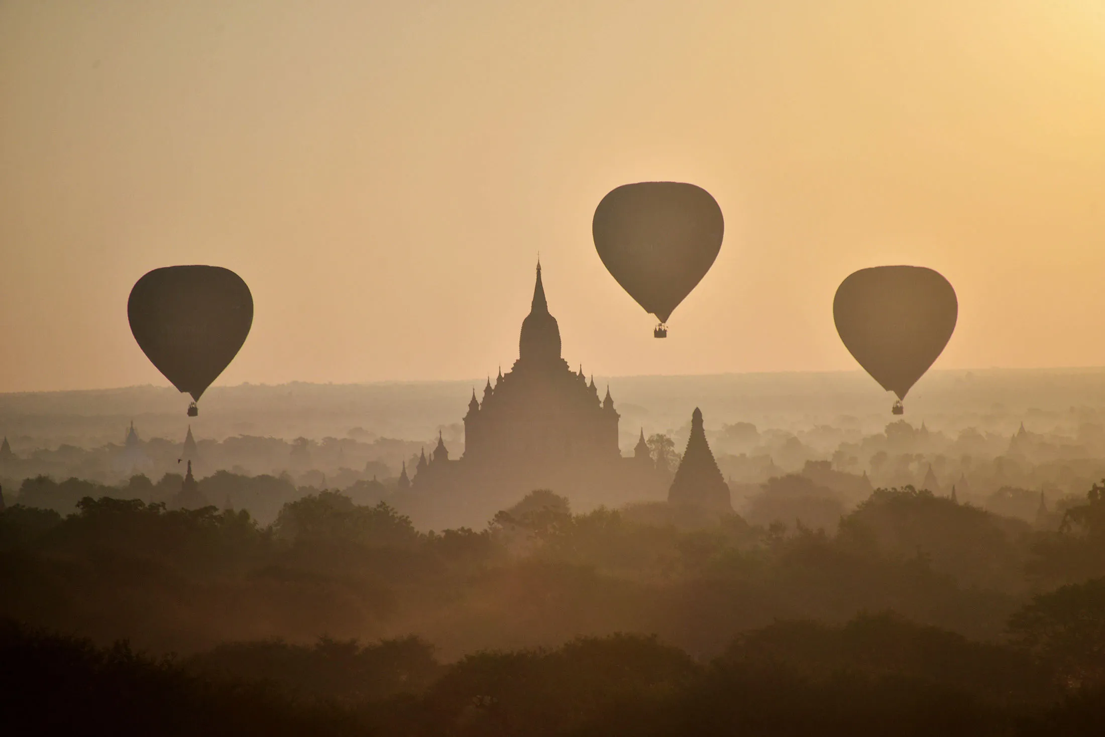 Hot air balloons fly over ancient temples in Bagan, northern Myanmar at sunrise on November 25, 2014.   AFP PHOTO/PHYO HEIN KYAW        (Photo credit should read Phyo Hein Kyaw/AFP/Getty Images)