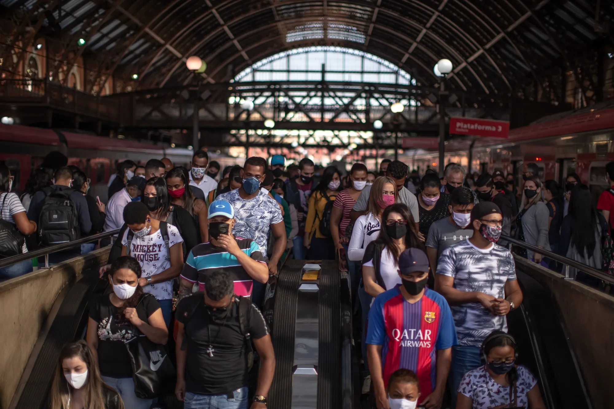 Commuters wearing protective masks walk onto excalators inside the Luz train station in Sao Paulo, Brazil, on&nbsp;June 22.