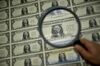 A magnifying glass is held over a 50 subject one dollar note sheet after being printed by an intaglio printing press in Washington, D.C., U.S.