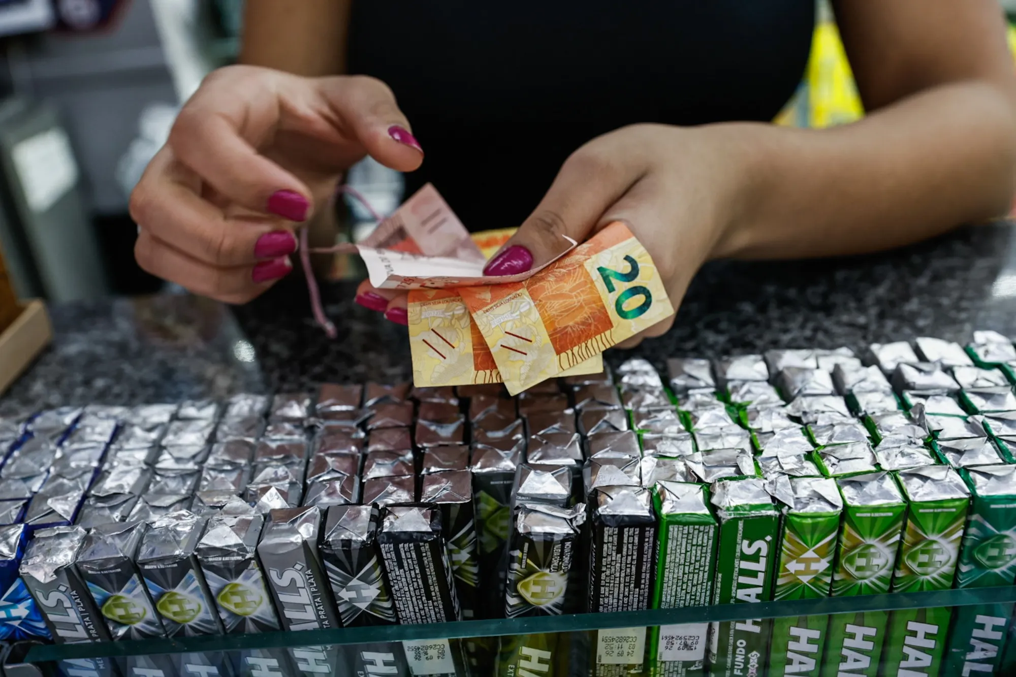 A merchant receives Brazilian real banknotes at a store in Sao Paulo.