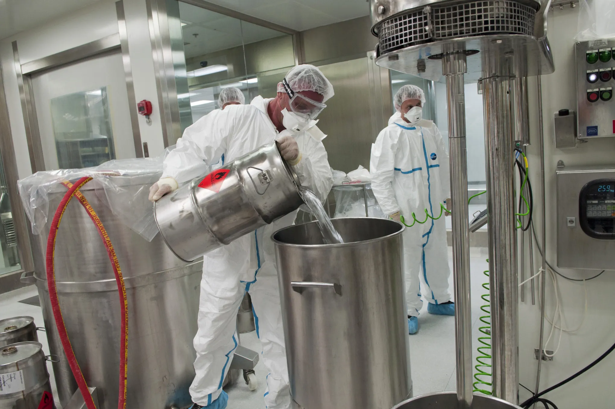 Employees wear protective clothing as they pour chemicals into a container in the tablet production plant at Teva Pharmaceutical Industries Ltd.'s headquarters in Jerusalem, Israel, on Sept. 19, 2011.