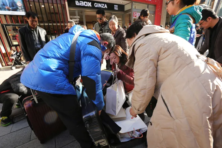 Chinese tourists pack purchases into suitcases outside a Laox&nbsp;store in the Ginza district of Tokyo.