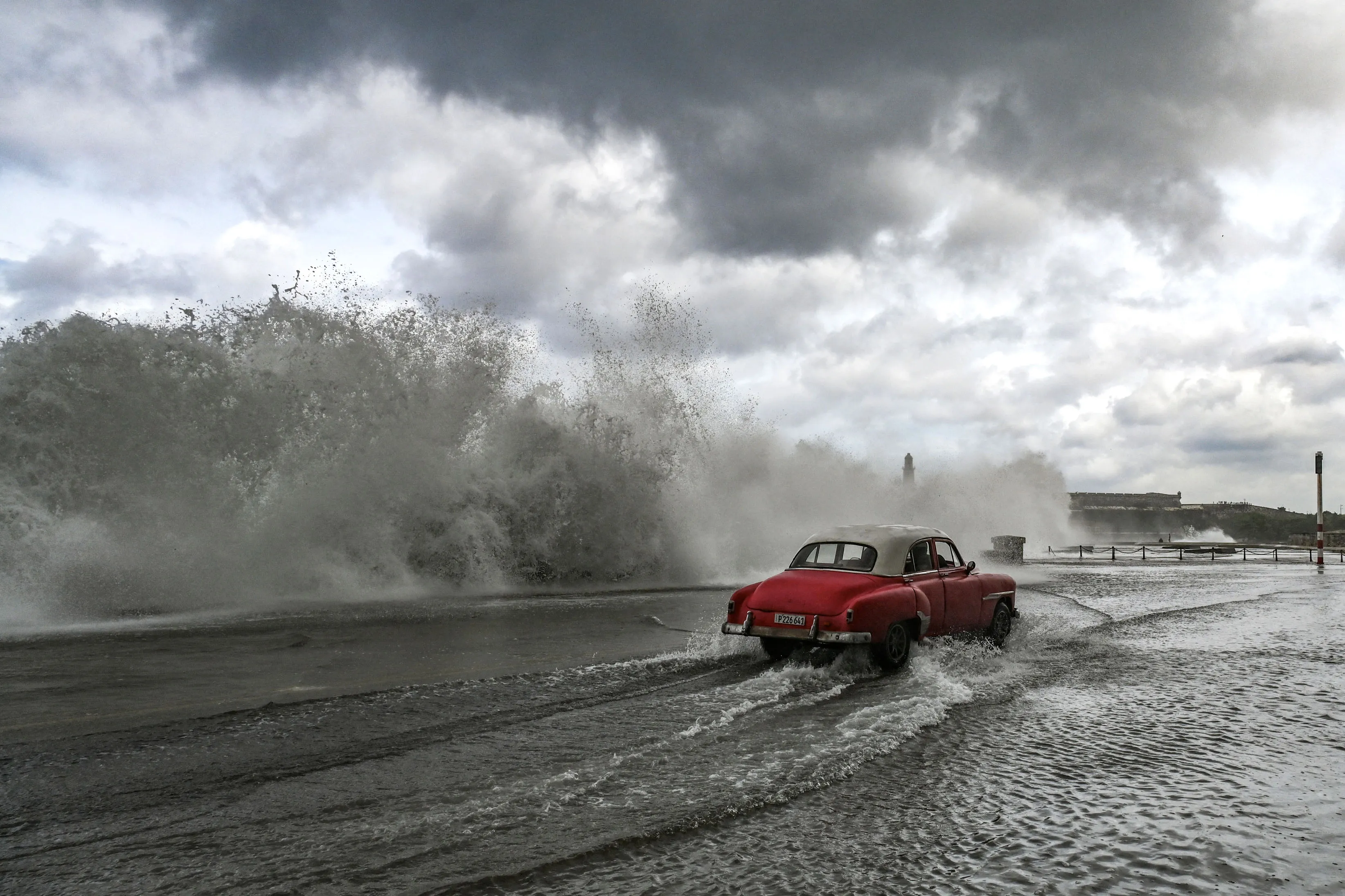 An old American car drives past waves crashing against the Malecon promenade in Havana, Cuba, due to the passage of Hurricane Milton.