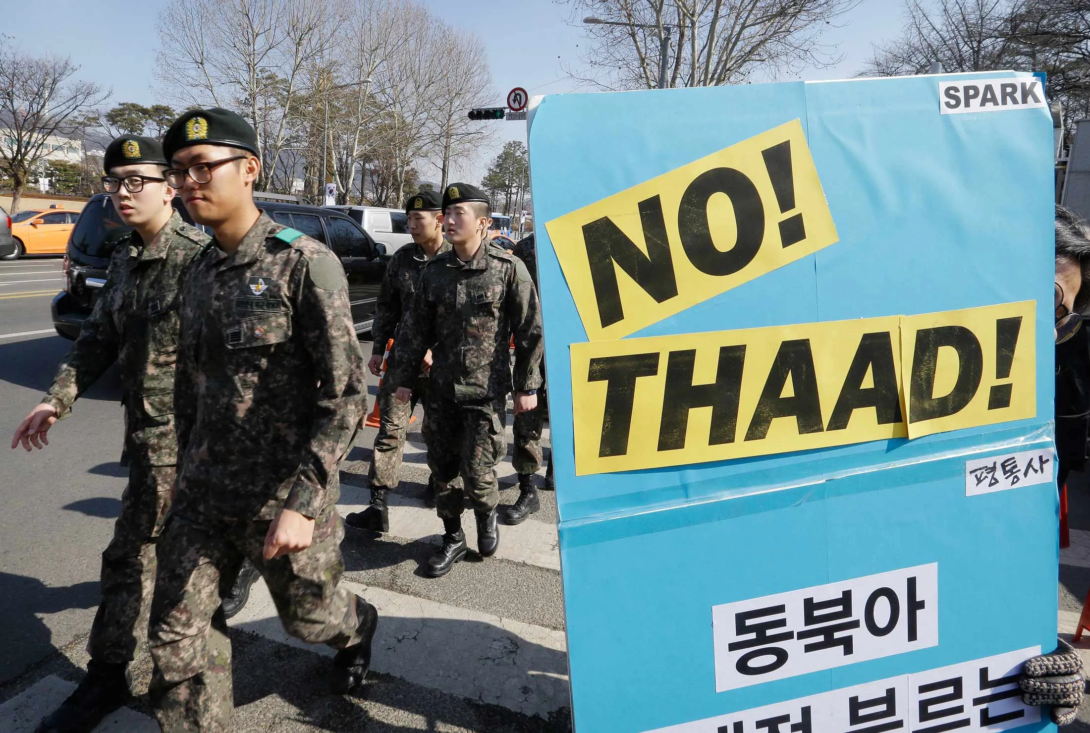 A South Korean protester participates in a rally to oppose the possible deployment of the United States' advanced defense system THAAD, a Terminal High-Altitude Area Defense, on Korea Peninsula, as South Korean army soldiers pass by in front of the Defense Ministry in Seoul, South Korea, Tuesday, Feb. 23, 2016.
