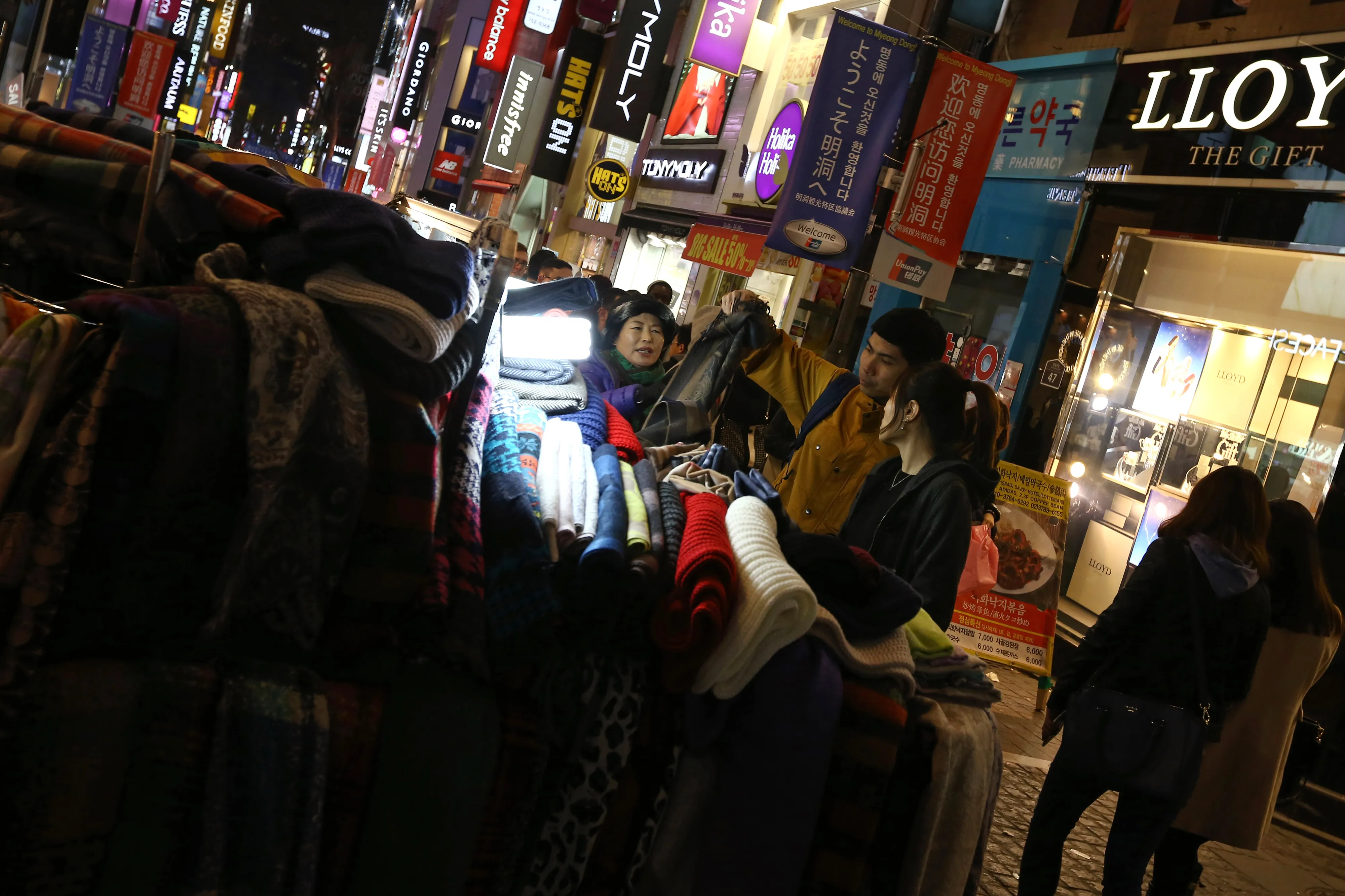 Shoppers browse scarfs at a street stall in the Myeongdong shopping district in Seoul, South Korea, on Sunday, Feb. 15, 2015.
