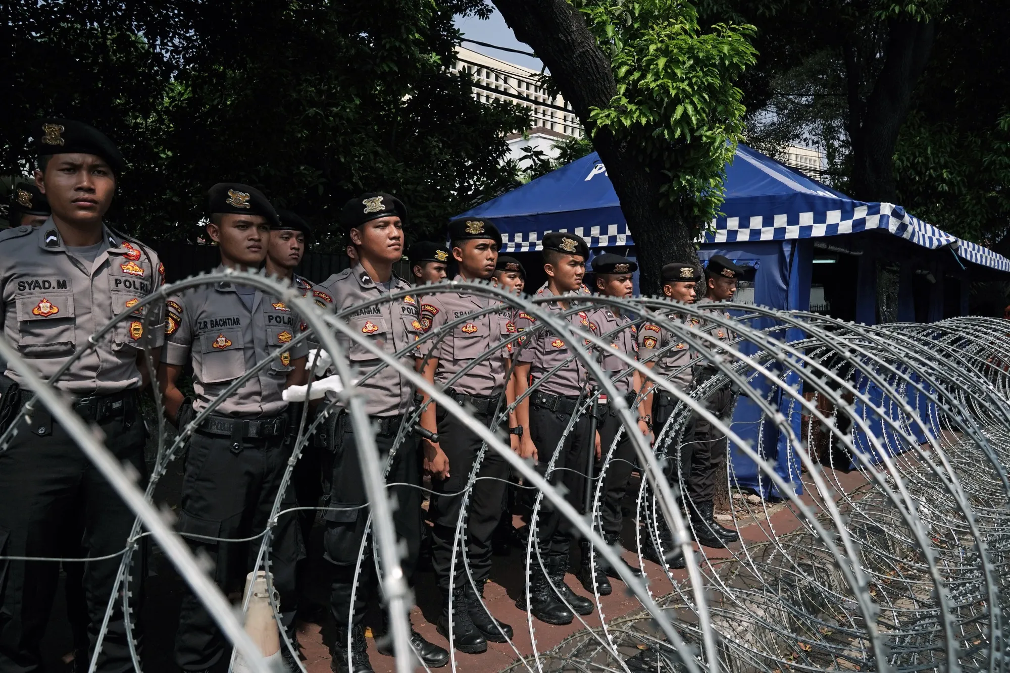 Members of the Indonesian National Police stand guard in front of barbed wire outside the General Election Commission in Jakarta on May 15, 2019.