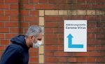 A man, wearing a face mask, walks past a sign guiding people to the entrance of a corona testing station at a hospital in Berlin.