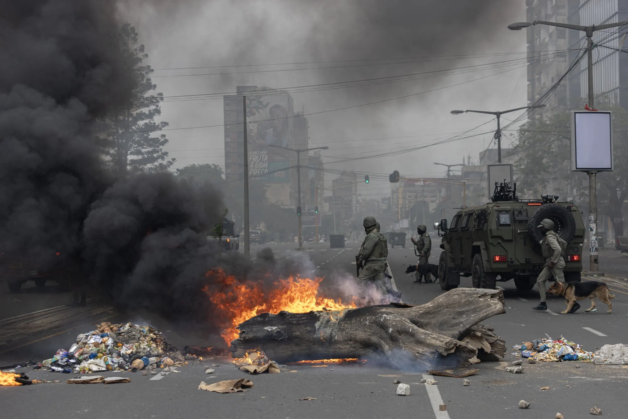 Anti-riot police officers walk down Eduardo Mondlane Avenue past burning barricades made by protesters in Maputo, Mozambique, on Nov. 7.&nbsp;